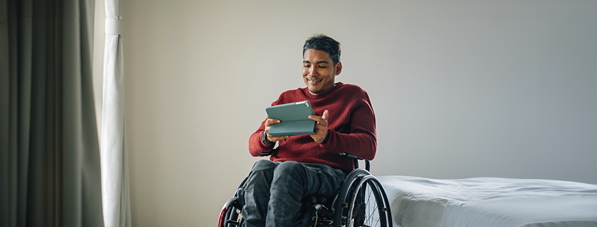 A man in a wheel chair using a tablet