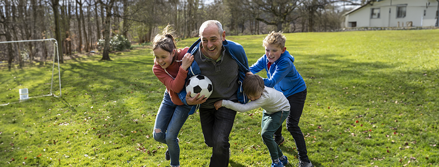 kids outside playing soccer with their dad